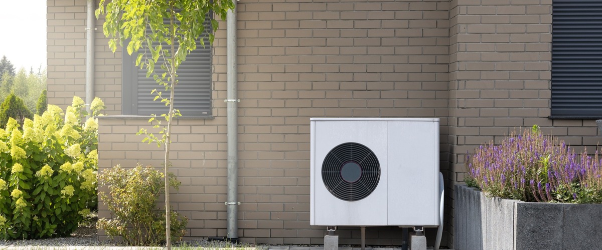 Bild zeigt eine Wärmepumpe an einer Hauswand verlinkt auf Blogbeitrag Wärmepumpen: Effizientes Heizen auch effizient versichern!