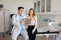Das Bild zeigt einen Arzt, der einer Patientin Informationen auf einem Tablet vorstellt.. 